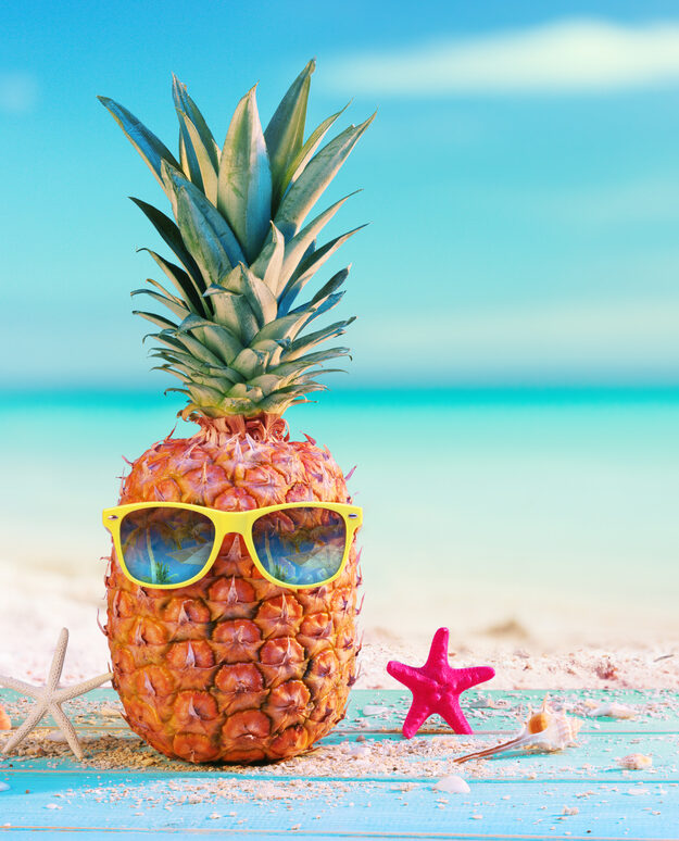 Ananas funky sur une plage, avec des lunettes de soleil.